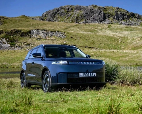 Black JAECOO E5 SUV parked on grass surrounded by hills