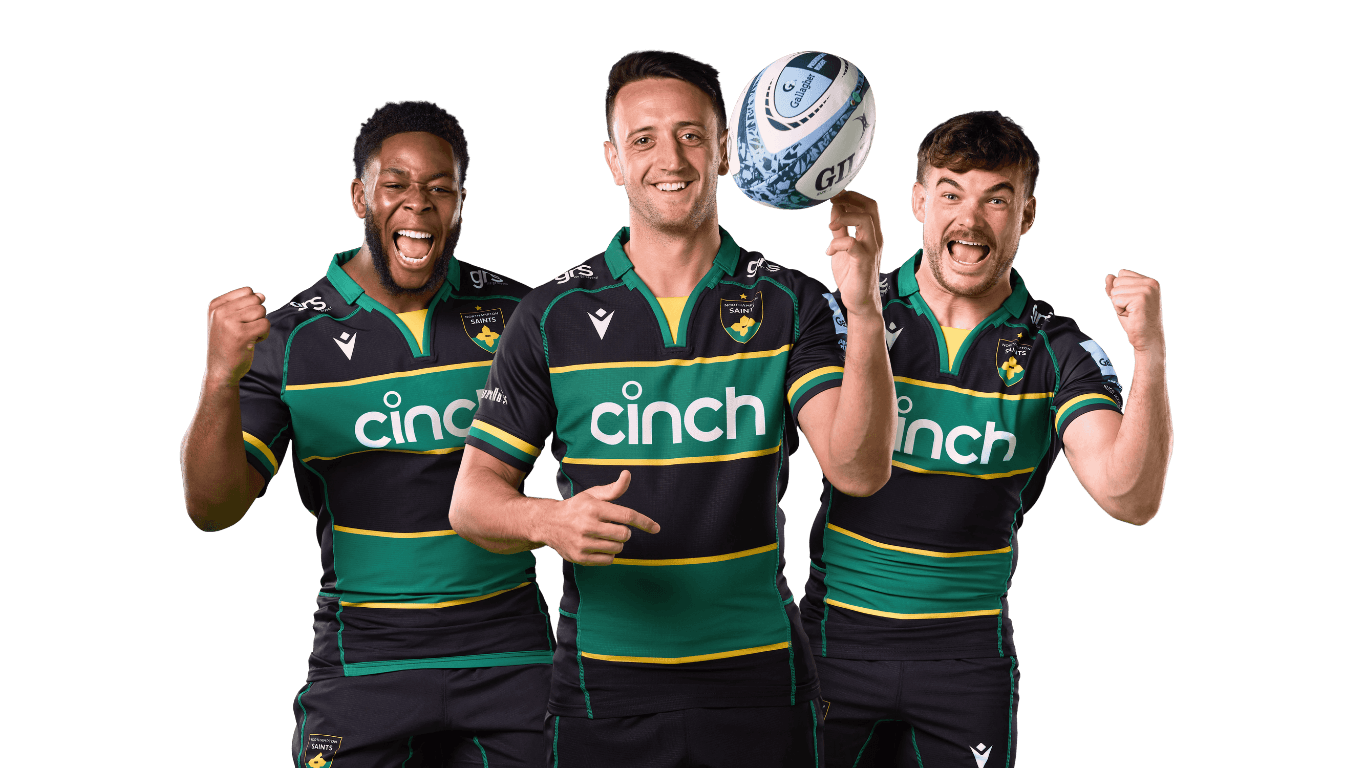 Three rugby players in black and green jerseys celebrate energetically, with one holding a rugby ball.