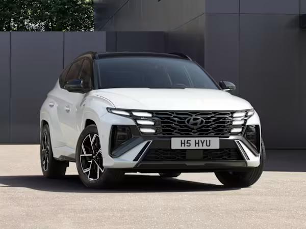 Hyundai TUSCON Hybrid car in white parked in front of a modern building