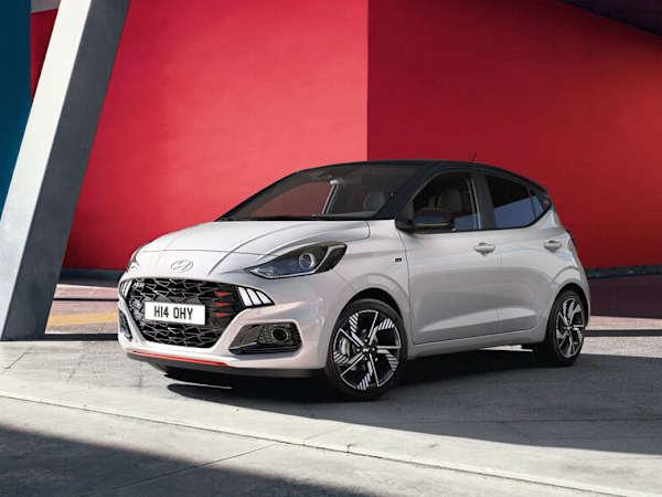 Hyundai i10 car in silver parked in front of a modern red building